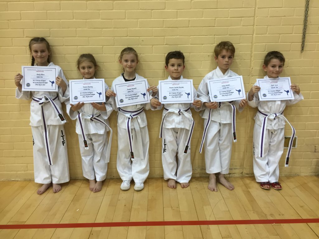 six Taekwondo students receiving their first belt and certificate at Torbay Taekwondo school